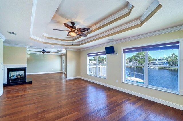 5449 Manatee Point Dr, New Port Richey, FL 34652 - unfurnished living room with a tray ceiling, ceiling fan, crown molding, wood finished floors, and a multi sided fireplace