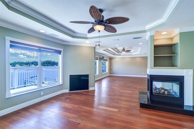 5449 Manatee Point Dr, New Port Richey, FL 34652 - unfurnished living room featuring ceiling fan, ornamental molding, a textured ceiling, a multi sided fireplace, and a tray ceiling