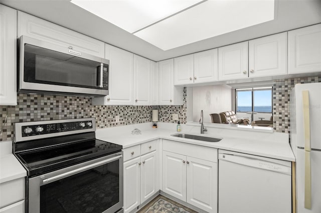 2616 Cove Cay Dr Unit 803, Clearwater, FL 33760 - kitchen featuring appliances with stainless steel finishes, a sink, decorative backsplash, and white cabinetry