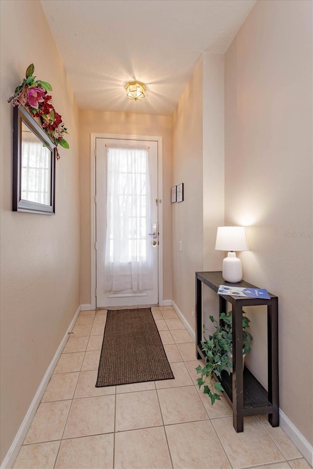 doorway to outside with light tile patterned flooring and baseboards