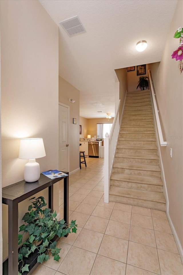 staircase featuring visible vents, tile patterned floors, and baseboards