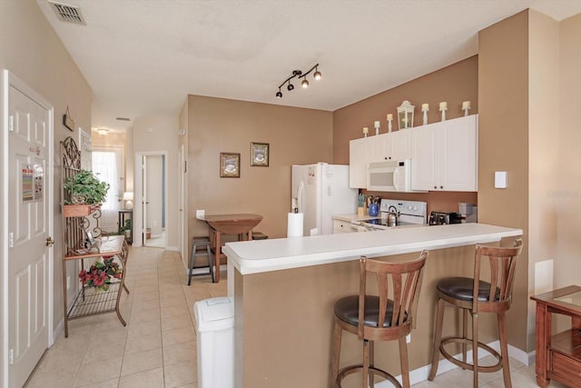 kitchen featuring light tile patterned floors, white appliances, visible vents, a peninsula, and light countertops