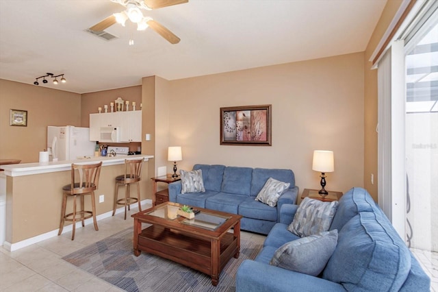living area with light tile patterned floors, rail lighting, baseboards, visible vents, and a ceiling fan