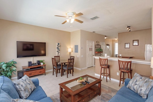 living room featuring light tile patterned floors, visible vents, a ceiling fan, and baseboards