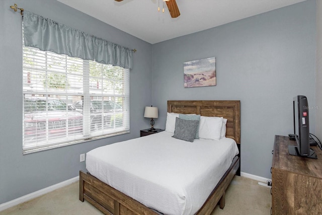 bedroom with light colored carpet, a ceiling fan, and baseboards