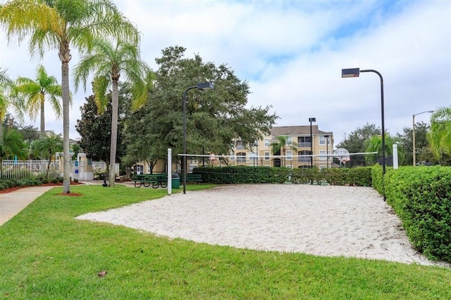 view of property's community featuring volleyball court, fence, and a yard