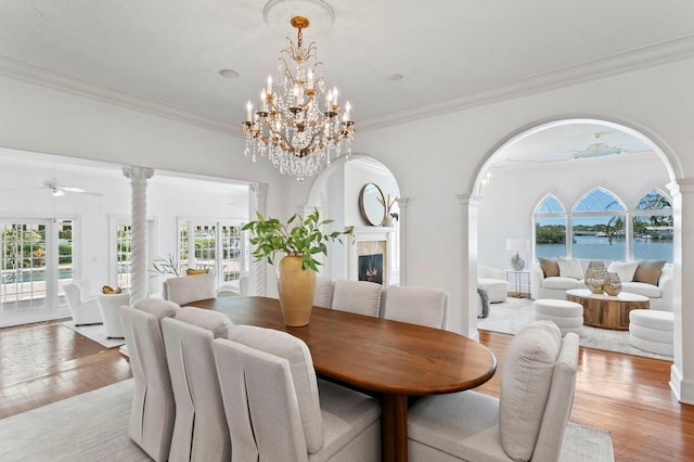 dining area featuring ornamental molding, a ceiling fan, light wood-style flooring, and a premium fireplace