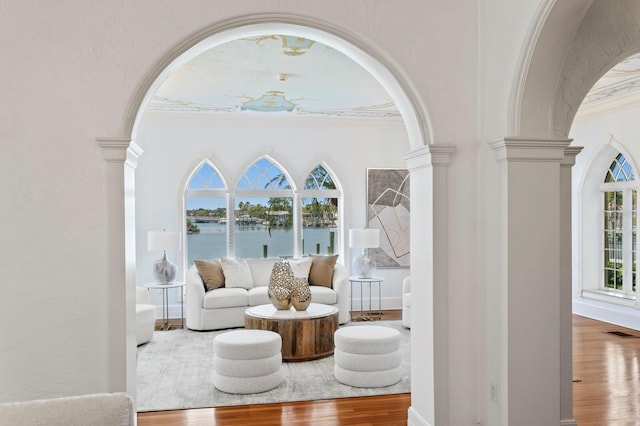 living area featuring visible vents, arched walkways, ornate columns, and wood finished floors