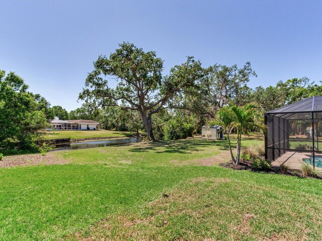 6310 95th St E, Bradenton, FL 34202 - view of yard featuring glass enclosure, a water view, an outdoor structure, and a shed