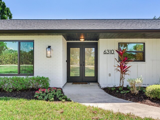 6310 95th St E, Bradenton, FL 34202 - view of exterior entry featuring french doors, roof with shingles, and brick siding