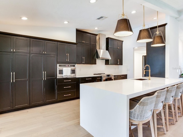 6310 95th St E, Bradenton, FL 34202 - kitchen with appliances with stainless steel finishes, a sink, a breakfast bar area, decorative light fixtures, and light wood-type flooring
