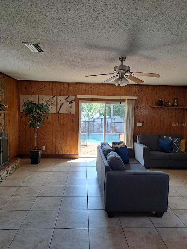 7503 N Howard Ave, Tampa, FL 33604 - living room with ceiling fan, a textured ceiling, visible vents, wood walls, and light tile patterned flooring