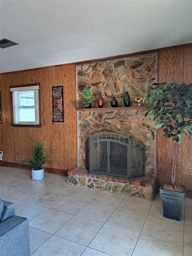 7503 N Howard Ave, Tampa, FL 33604 - unfurnished living room with a stone fireplace, a textured ceiling, visible vents, wood walls, and tile patterned floors