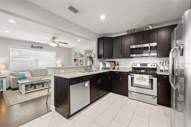 4519 S Grady Ave, Tampa, FL 33611 - kitchen with stainless steel appliances, a sink, open floor plan, light stone counters, and a peninsula