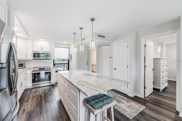 kitchen with dark wood-style floors, stainless steel appliances, visible vents, a breakfast bar area, and white cabinetry