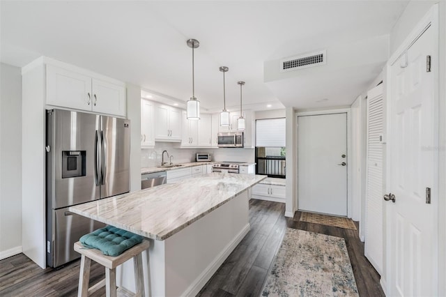 kitchen with a sink, white cabinets, dark wood finished floors, appliances with stainless steel finishes, and visible vents