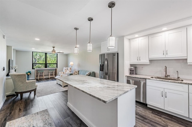 kitchen featuring stainless steel appliances, white cabinetry, a sink, a kitchen island, and dark wood-style flooring