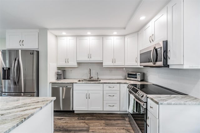 kitchen featuring stainless steel appliances, dark wood-style floors, a sink, recessed lighting, and white cabinetry