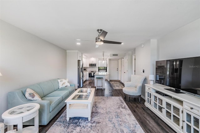 living room with dark wood-type flooring, visible vents, and a ceiling fan