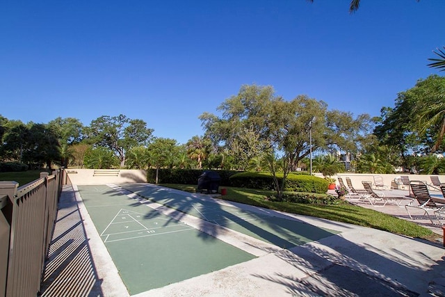view of property's community with fence and shuffleboard