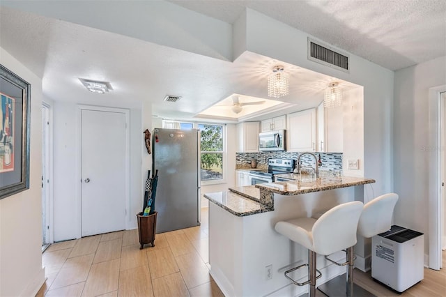 kitchen with light stone countertops, visible vents, white cabinetry, and appliances with stainless steel finishes