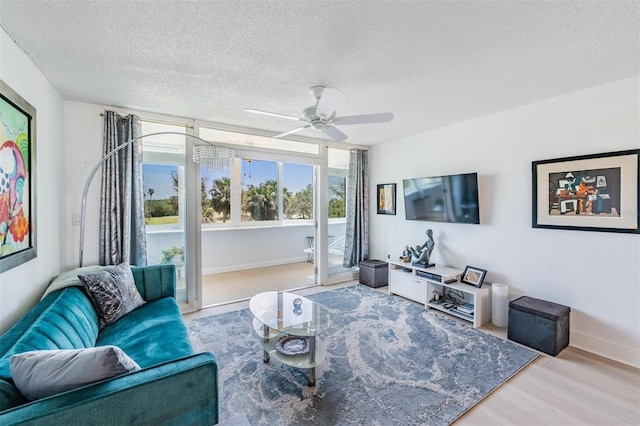 living area with wood finished floors, a textured ceiling, baseboards, and ceiling fan