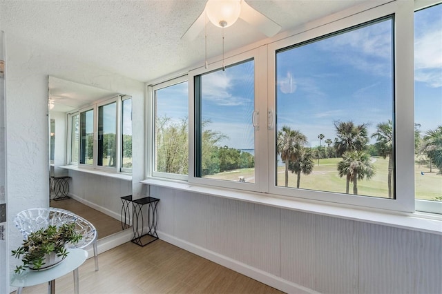 sunroom / solarium featuring baseboards, wood finished floors, and a textured ceiling
