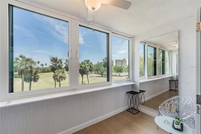 sunroom / solarium with wood finished floors, a textured ceiling, and baseboards