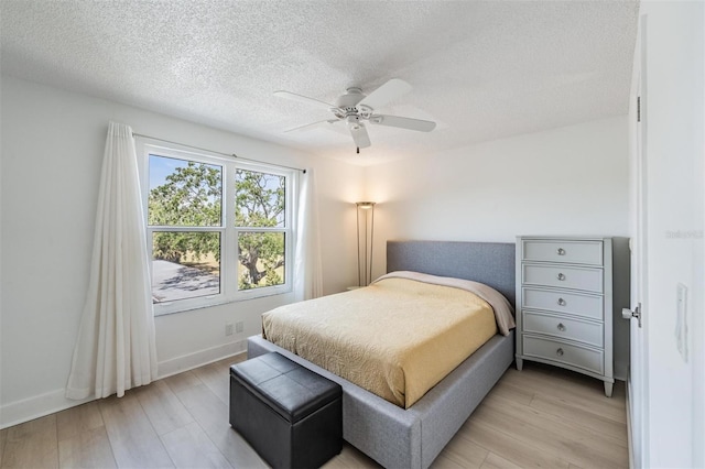bedroom featuring baseboards, a textured ceiling, light wood-style floors, and ceiling fan