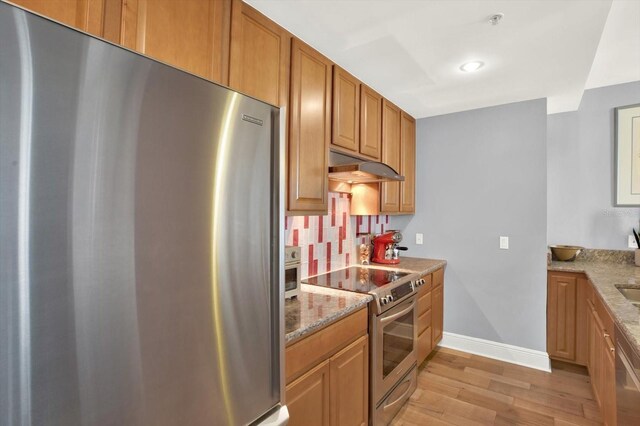 1238 E Kennedy Blvd Unit 702, Tampa, FL 33602 - kitchen featuring stainless steel appliances, light wood finished floors, under cabinet range hood, light stone countertops, and backsplash