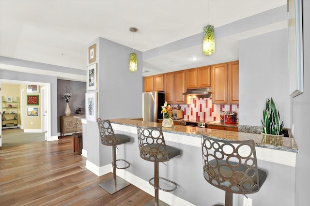 1238 E Kennedy Blvd Unit 702, Tampa, FL 33602 - kitchen featuring stainless steel appliances, a peninsula, a kitchen breakfast bar, light wood-style floors, and light stone countertops