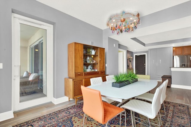 1238 E Kennedy Blvd Unit 702, Tampa, FL 33602 - dining space with a chandelier, light wood-style floors, baseboards, and a tray ceiling