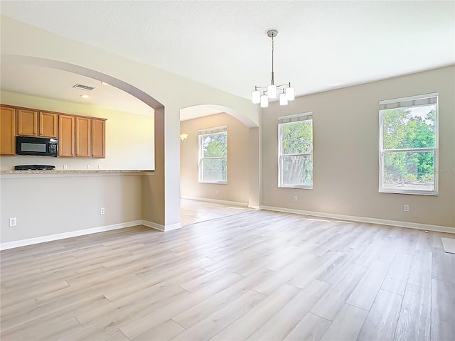 1705 Plantation Pointe Dr, Orlando, FL 32824 - kitchen featuring black microwave, open floor plan, light wood finished floors, brown cabinetry, and hanging light fixtures
