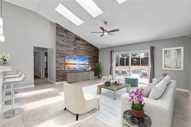 living area with visible vents, baseboards, ceiling fan, high vaulted ceiling, and a skylight