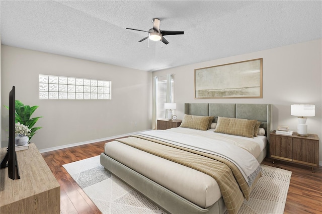 bedroom with a textured ceiling, baseboards, a ceiling fan, and wood finished floors