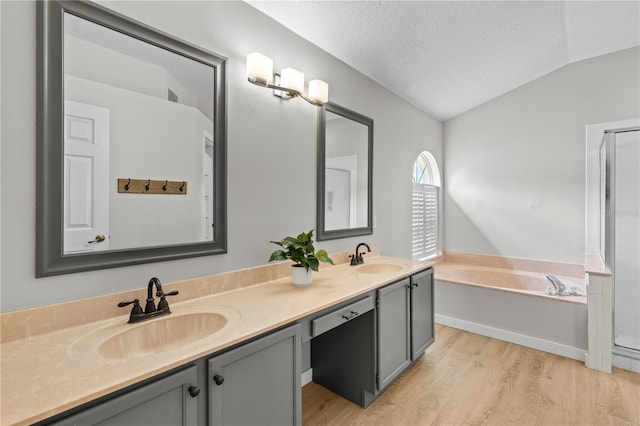 full bathroom featuring a sink, lofted ceiling, wood finished floors, and a bath