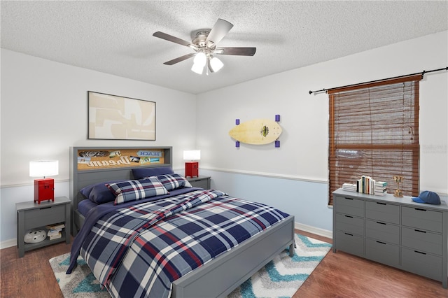 bedroom with baseboards, a textured ceiling, and wood finished floors