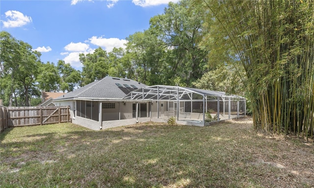 back of property featuring a fenced backyard, glass enclosure, and a yard
