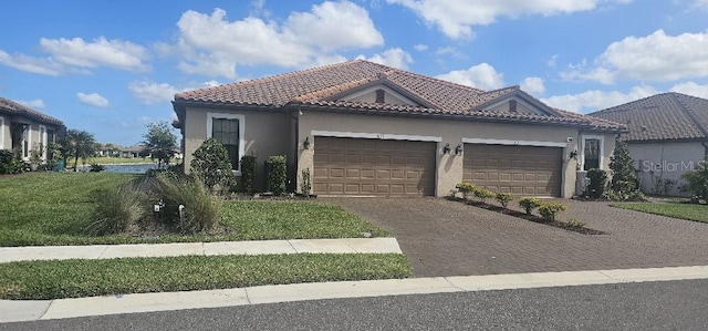 mediterranean / spanish-style home with decorative driveway, an attached garage, a tile roof, and stucco siding