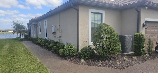 view of side of property with a garage, central AC unit, and stucco siding