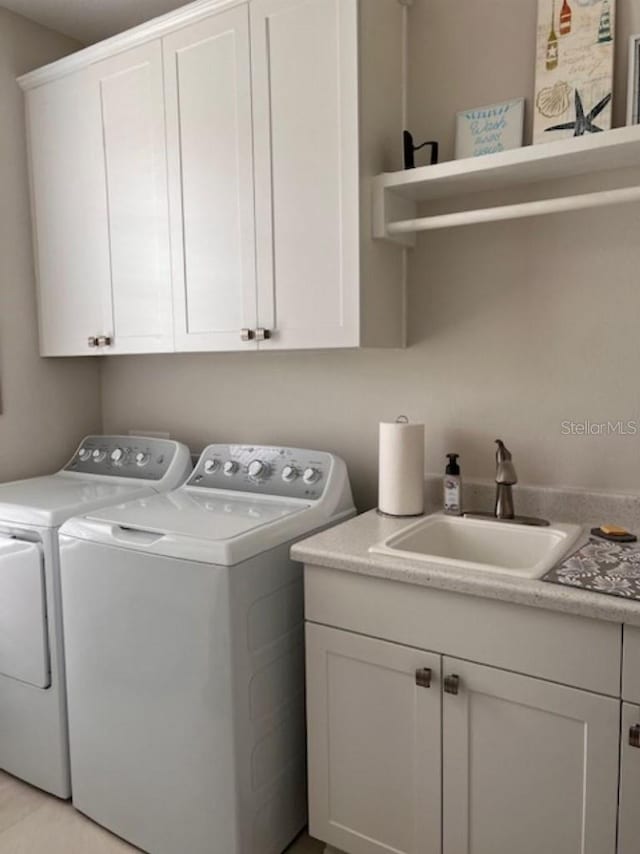 washroom featuring cabinet space, washing machine and dryer, and a sink