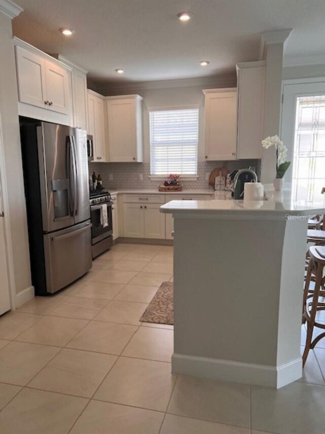 kitchen with crown molding, range with gas stovetop, a peninsula, stainless steel fridge, and backsplash