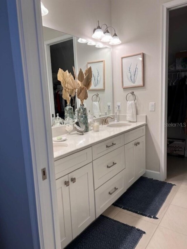 bathroom featuring a notable chandelier, a sink, tile patterned flooring, double vanity, and a spacious closet