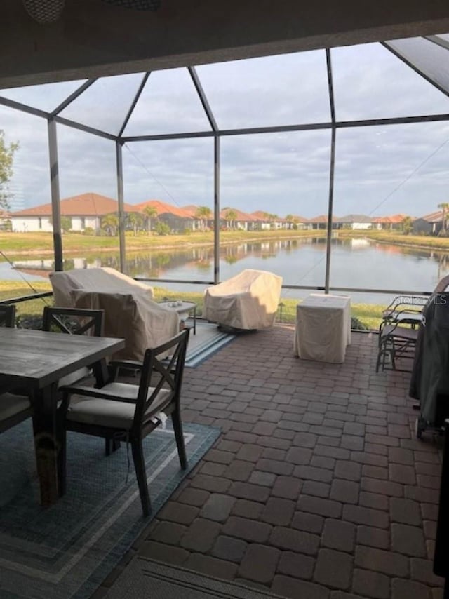 view of patio / terrace with glass enclosure, a water view, a residential view, and outdoor dining space