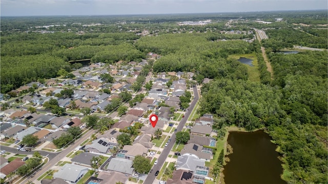 aerial view of property and surrounding area featuring a nearby body of water, nearby suburban area, and a forest