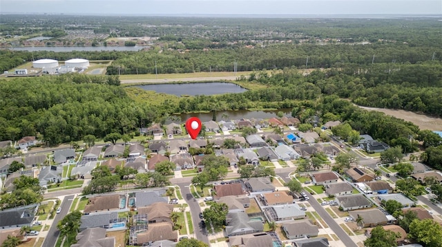 view of property location featuring a large body of water, a heavily wooded area, and nearby suburban area