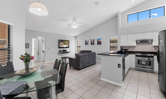 kitchen with electric stove, a peninsula, light tile patterned floors, ceiling fan, and high vaulted ceiling