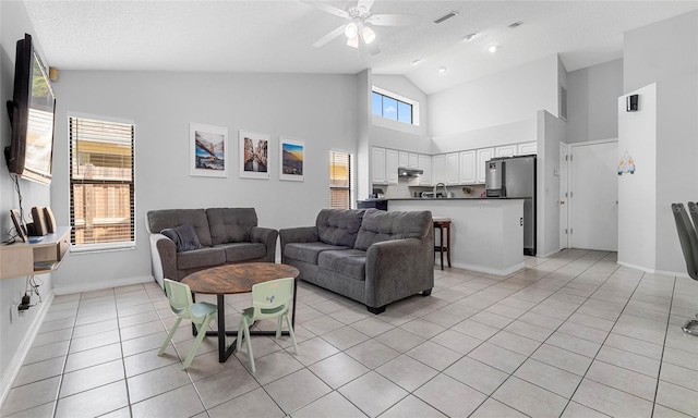 living area with ceiling fan, high vaulted ceiling, light tile patterned floors, and baseboards