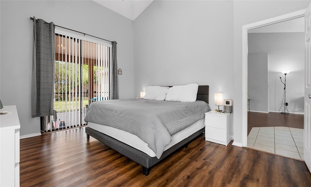 bedroom featuring access to exterior, wood finished floors, baseboards, and high vaulted ceiling
