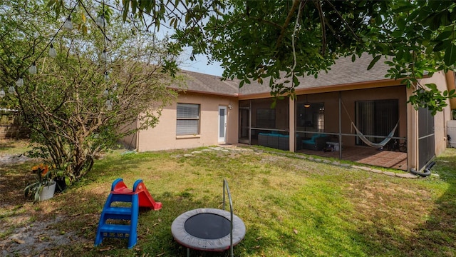 rear view of house with stucco siding, a lawn, and a shingled roof